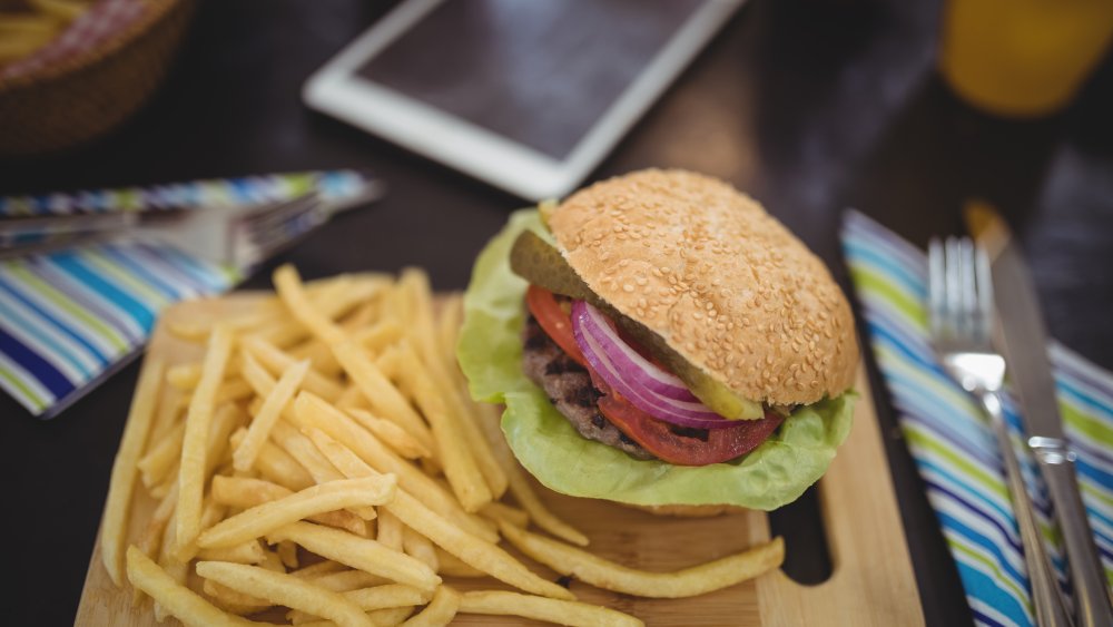 Fast food burger and fries with smart phone in background