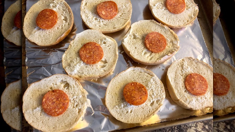 A tray of bagels with slices of pepperoni 