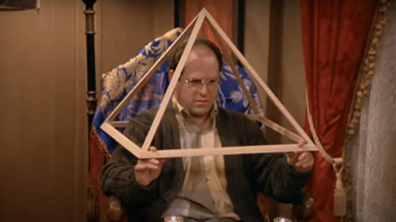 George Costanza inside a wooden triangle 