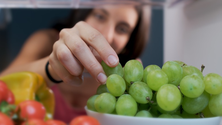 Woman reaching for grapes in a bowl