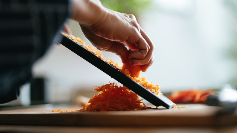 person grating carrots with hand grater