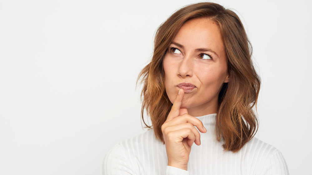 Woman thinking in white sweater