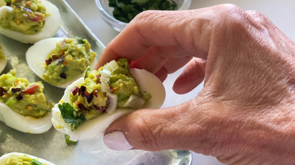 holding guacamole deviled eggs