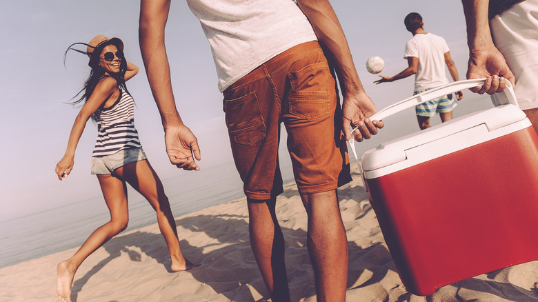 people carrying cooler on beach