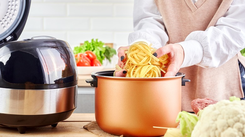 person putting noodles in crockpot