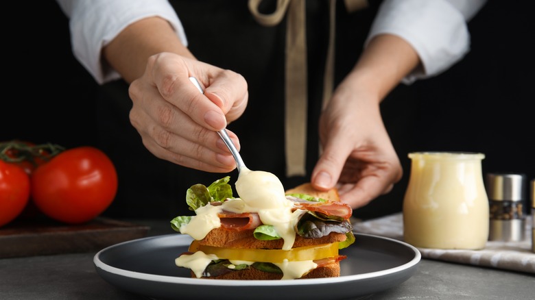 mayonnaise being spread on sandwich