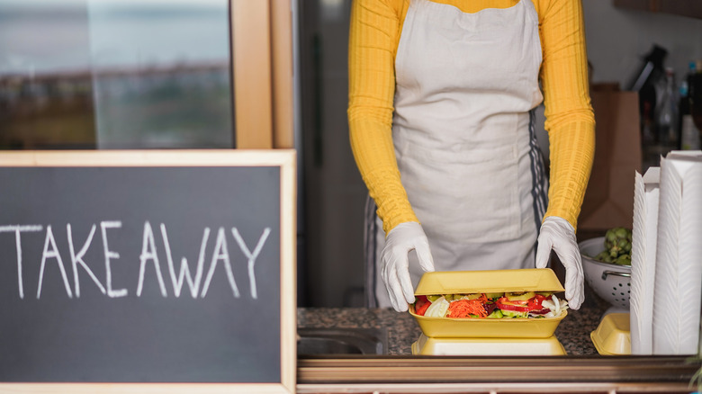 A food truck employee packing up a takeaway order