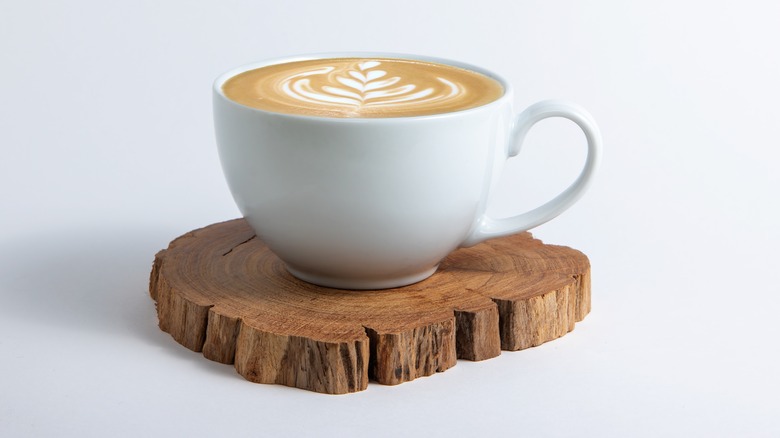 Flat white coffee in cup on wooden coaster