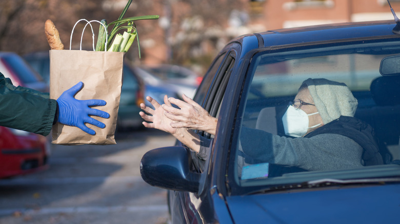 Volunteer handing food donation to car passenger