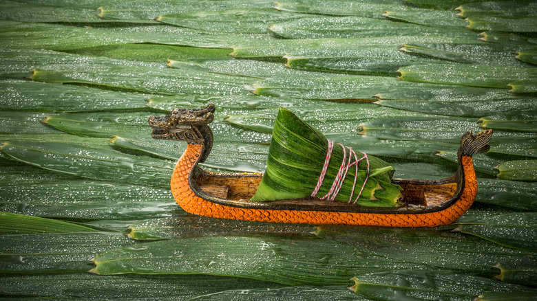 MIni dragon boat with dumpling on background of leaves