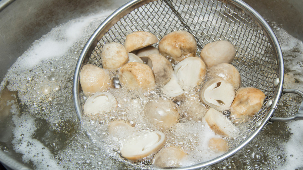 Mushrooms in strainer over water