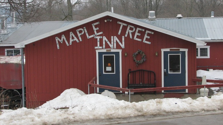 Red farmhouse exterior of Maple Tree Inn during winter