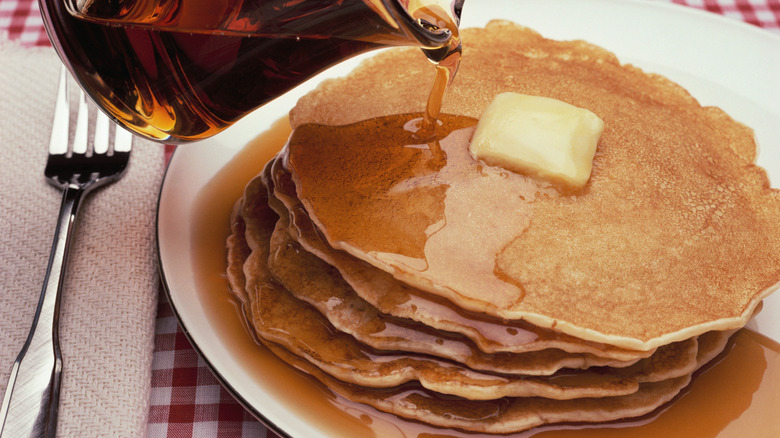 Syrup pouring over stack of pancakes in restaurant