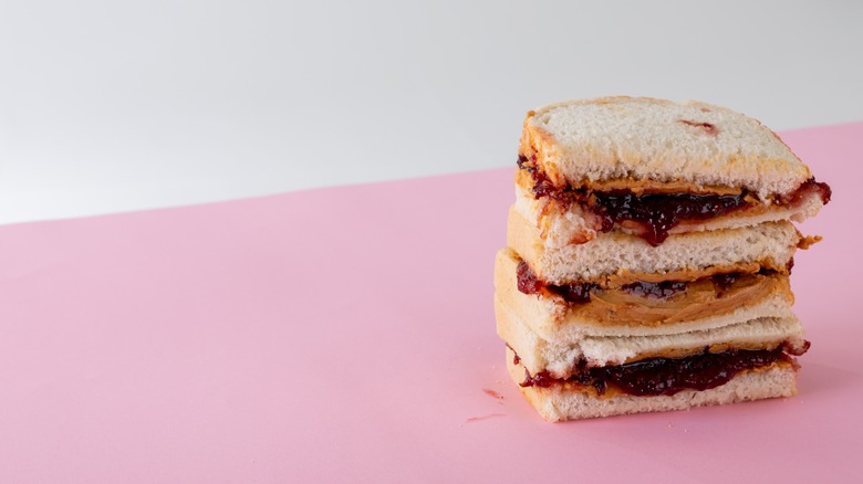 A stack of PB&J sandwiches on pink and white background