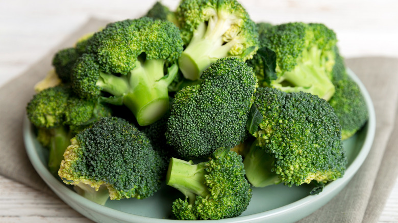 broccoli head and florets on a wooden cutting board