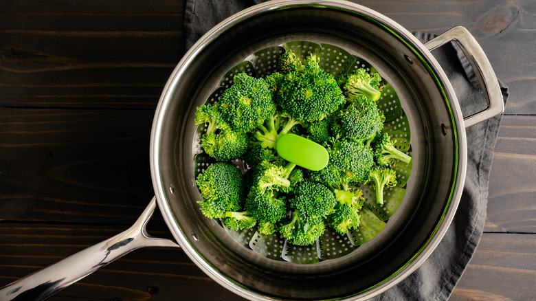 blanching raw broccoli in a steamer basket