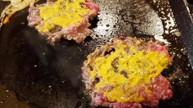 Burger patties with mustard on grill