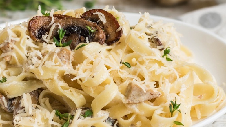 alfredo pasta topped with cheese and mushrooms