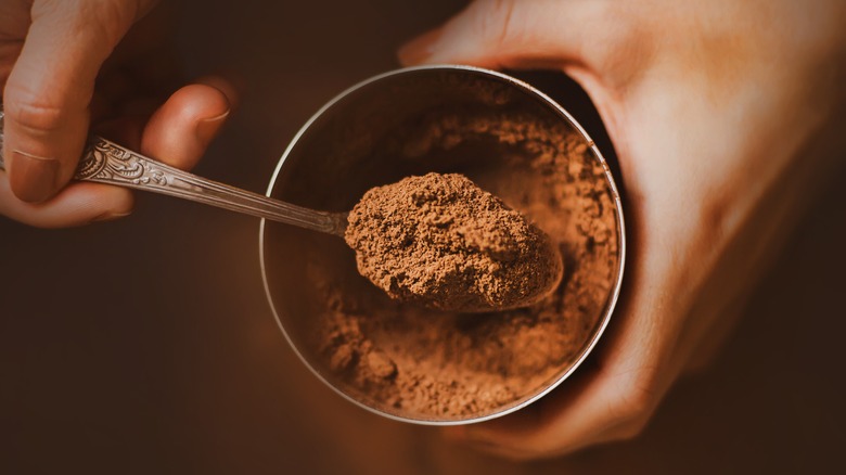 person spooning cocoa powder