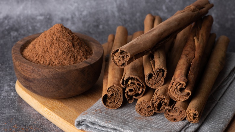 Ground cinnamon and cinnamon sticks on wood cutting board