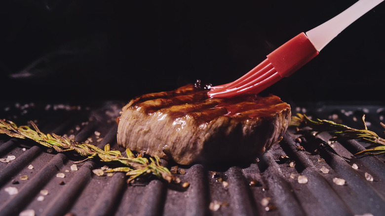 brushing sauce on grilling steak