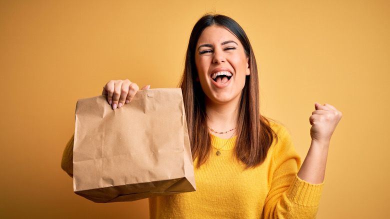 happy woman with brown takeout bag