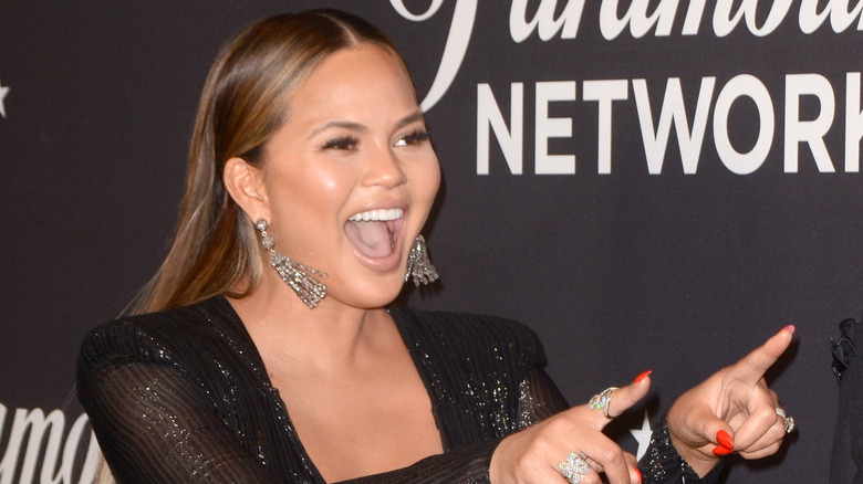 Chrissy Teigen pointing fingers with wide smile