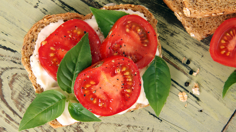 open faced tomato sandwich on rustic table