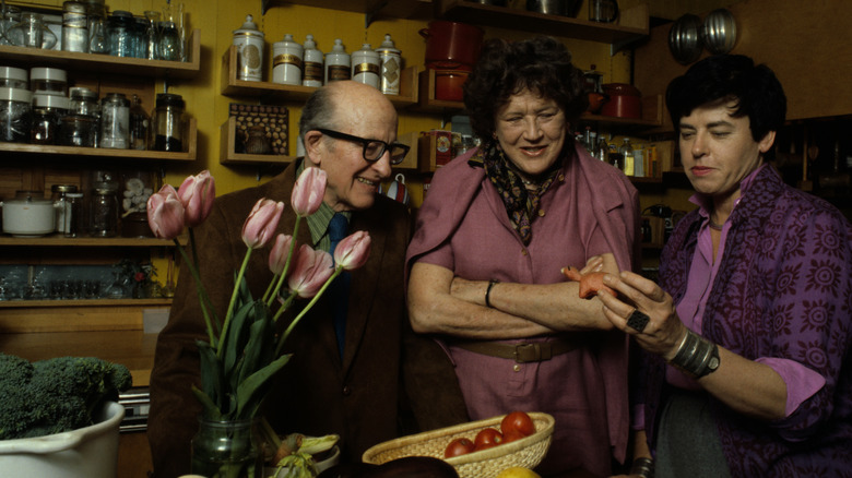 Julia Child standing with two people in a kitchen