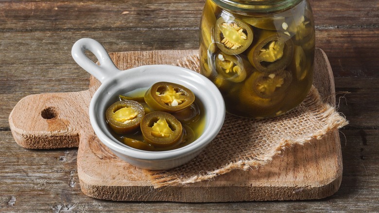 Jalapeño slices in a small bowl on a cutting board