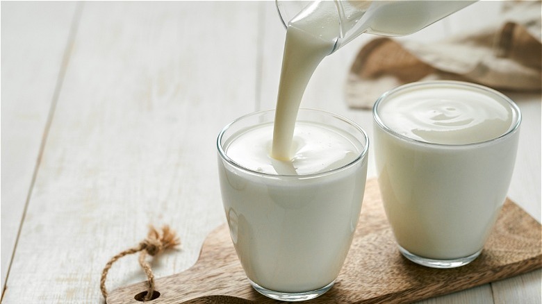 Buttermilk being poured into glass next to glass of yogurt