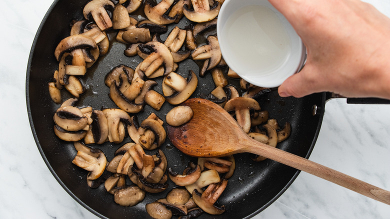 hand pouring stuff on mushrooms