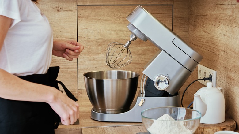 Person in front of stand mixer with bowl of flour near it