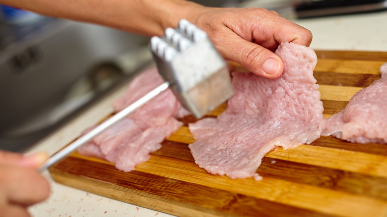 Person using meat mallet