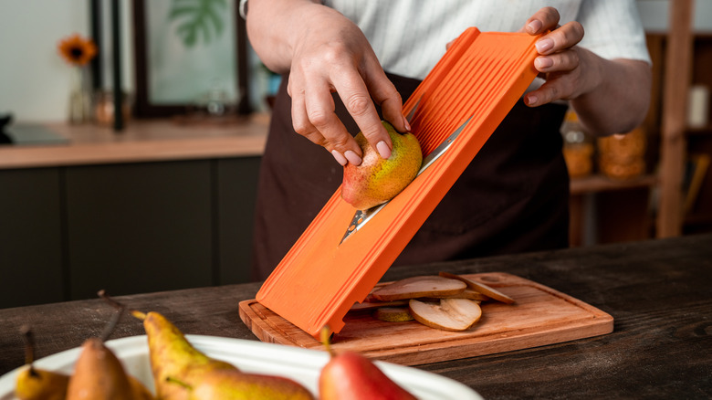 Someone using a mandoline without the guard