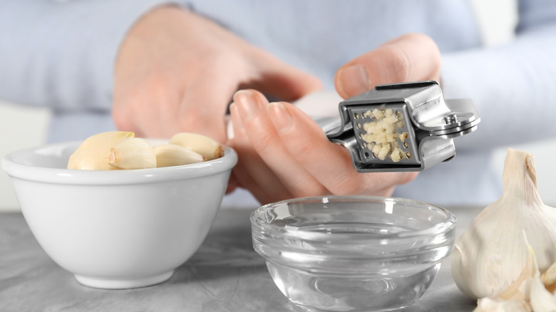 Person crushing garlic with a garlic press