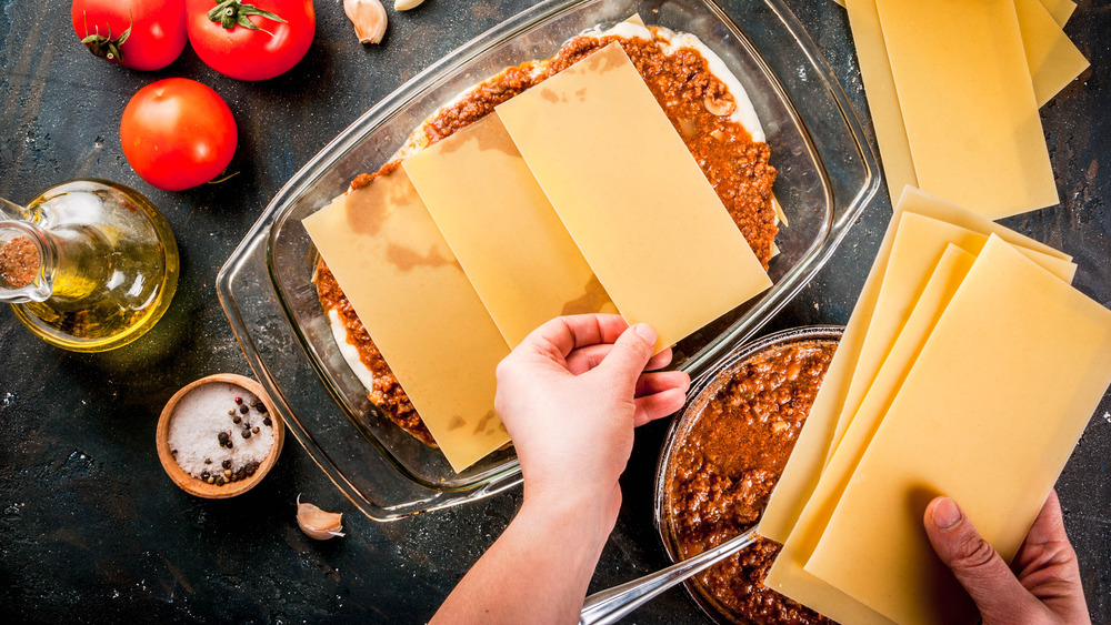 layering uncooked pasta into a lasagna