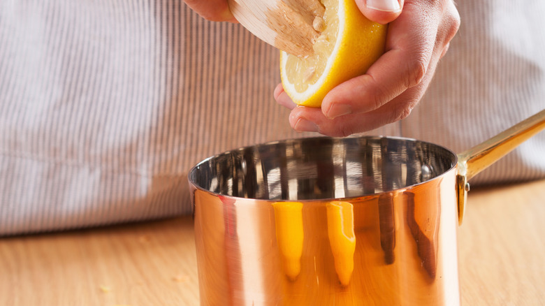 man squeezing lemon into pot