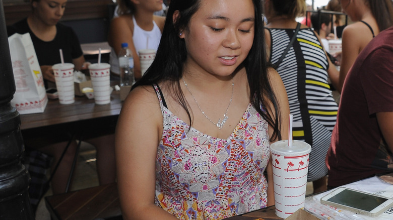 Girl eating In-N-Out with a drink 