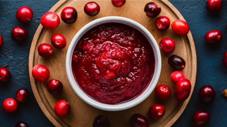 Bowl of cranberry sauce surrounded by whole cranberries