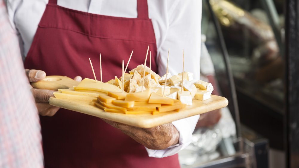 Employee holding cutting board with cheese samples