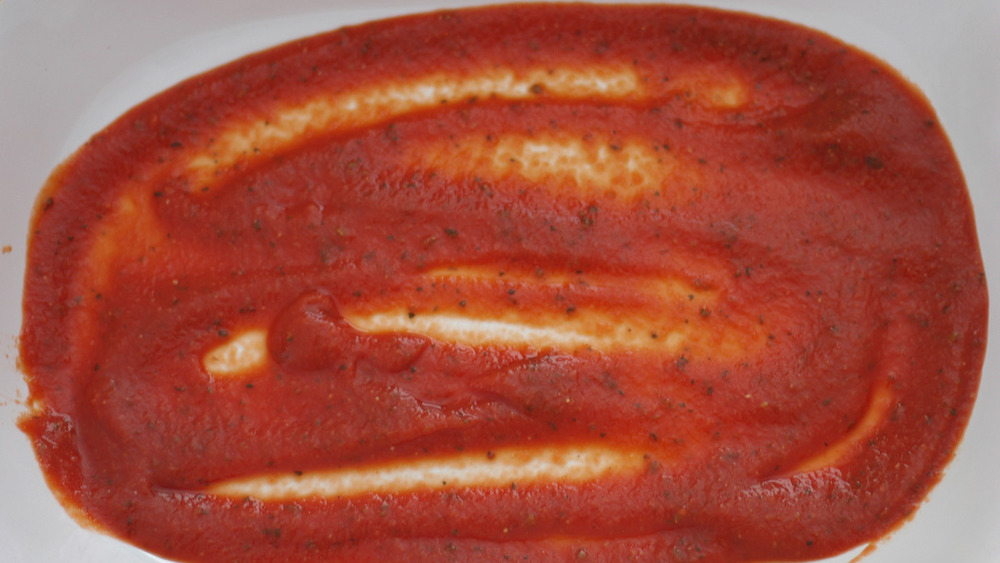 manicotti sauce at the bottom of baking dish