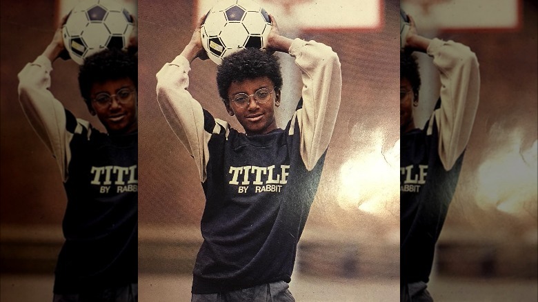 A young marcus samuelsson holds a soccer ball over his head