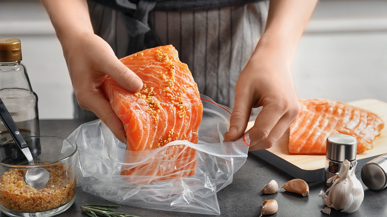 Putting salmon in a plastic bag to marinate