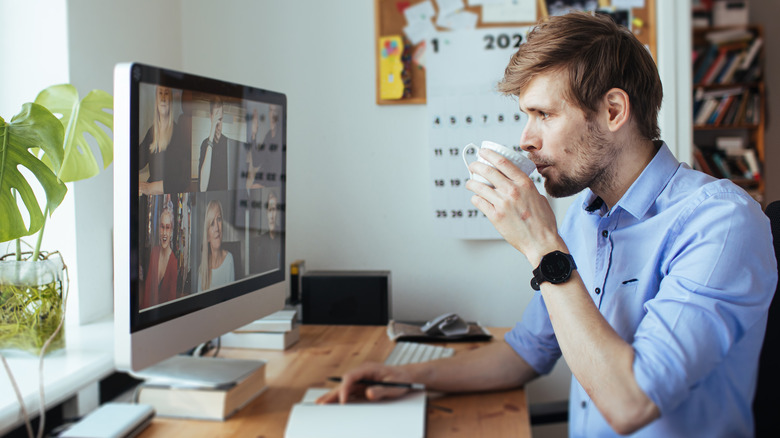 Drinking coffee by the computer