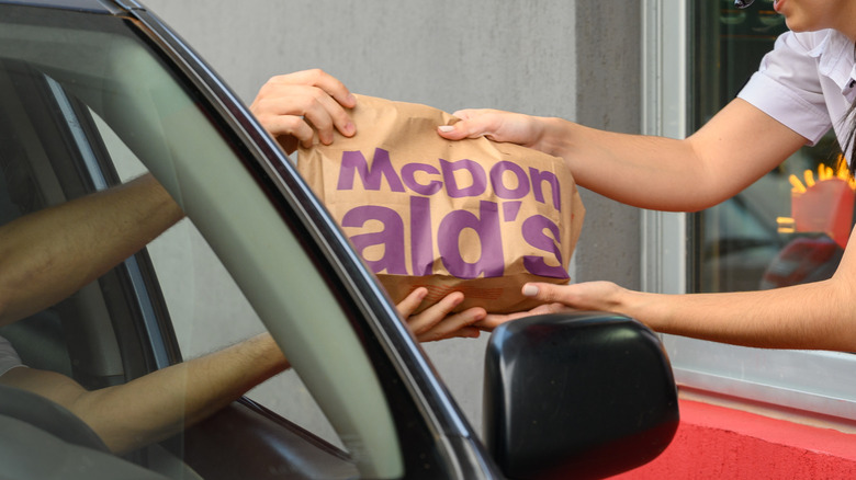 McDonald's worker handing food to drive-thru customer