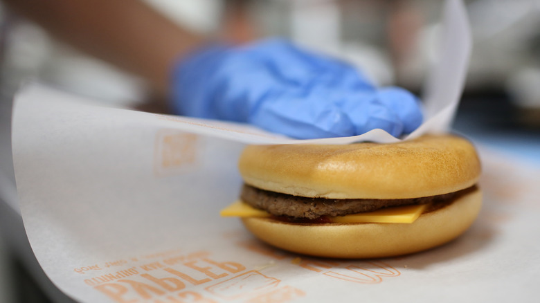 An Employee wrapping a Mcdonalds Cheeseburger