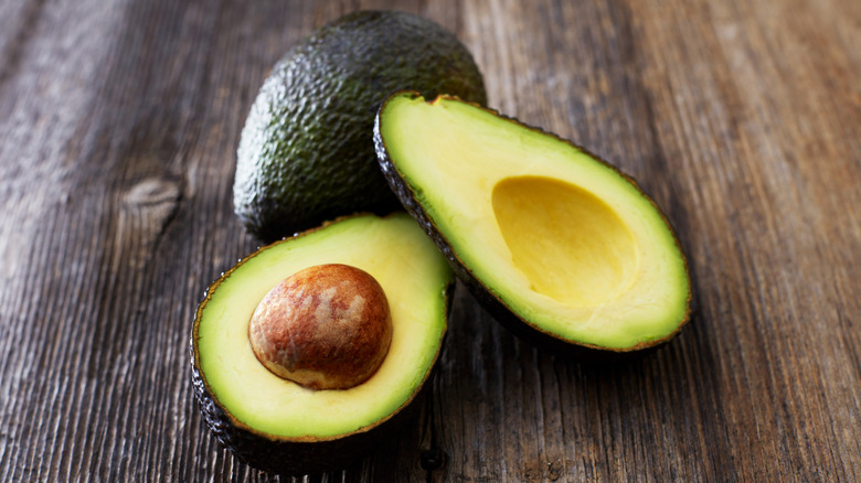 Split avocado on wooden table