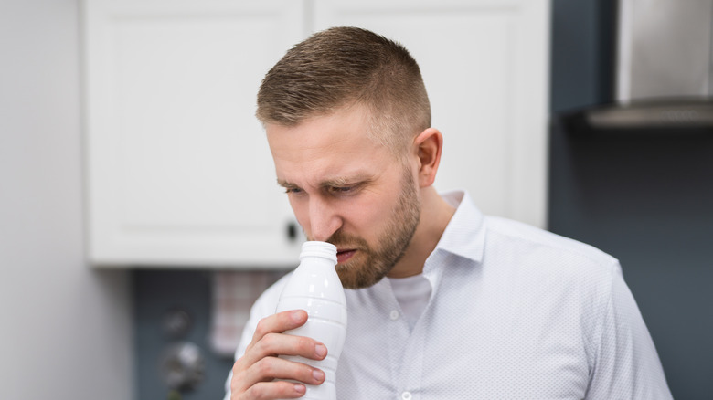 man smelling milk bottle