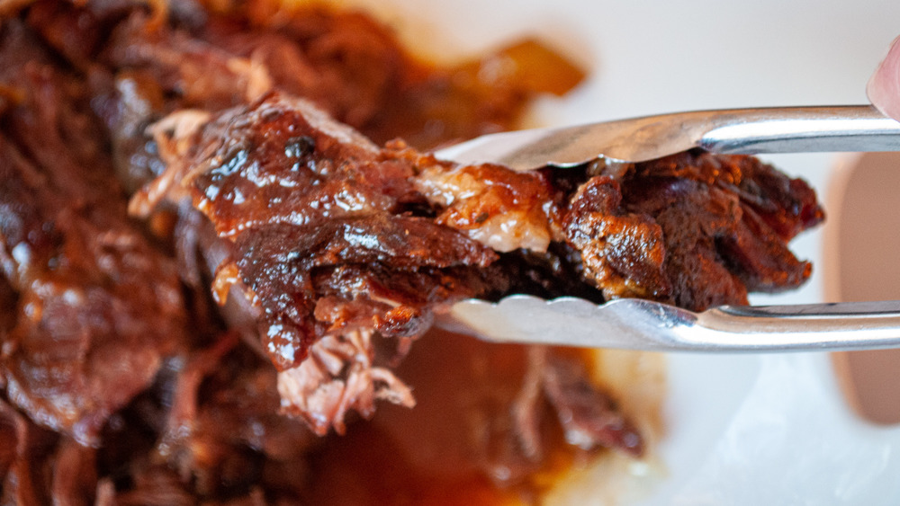 tongs holding Mississippi pot roast meat